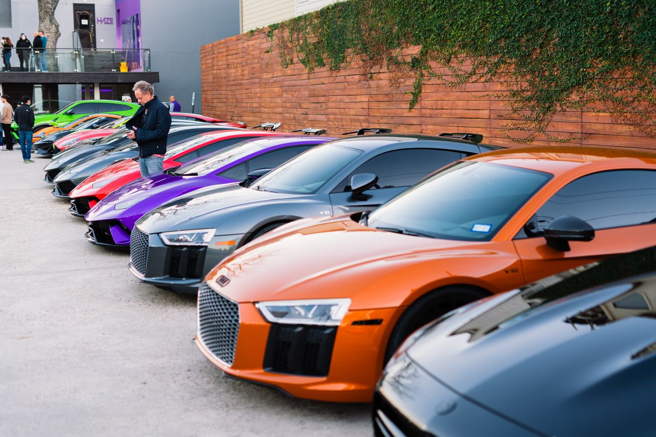 A lineup of luxury sports cars parked outdoors during a vibrant car show event.