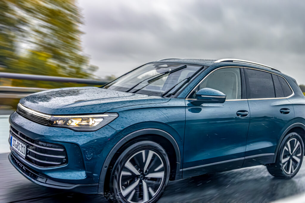 blue suv driving on wet road in rain. modern car on rainy highway.